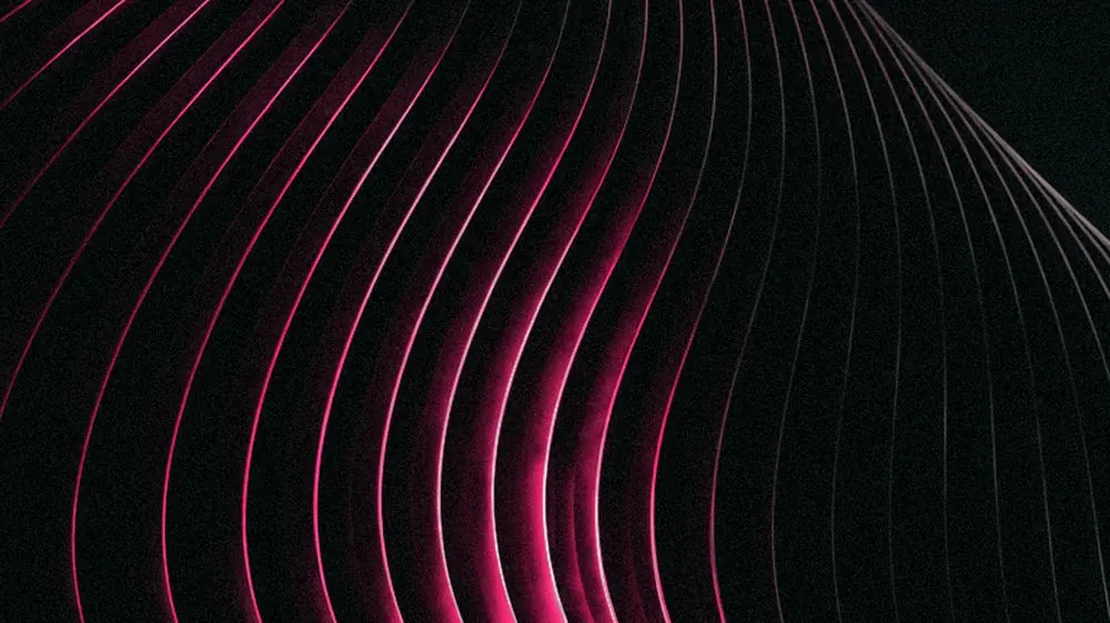 Uma superfície de nervuras paralelas curvando-se em repetição, metade em magenta, metade em sombra.